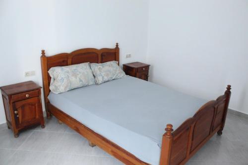 1 dormitorio con 1 cama de madera y 2 mesitas de noche en Studio en Oued Laou