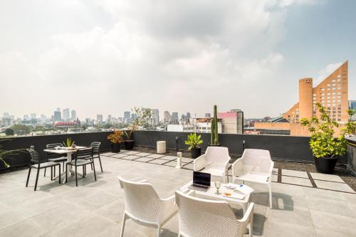 a rooftop patio with white chairs and tables and a city skyline at ULIV Antara in Mexico City