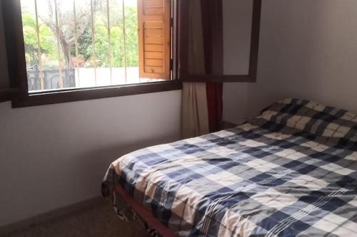 um quarto com uma cama xadrez em frente a uma janela em Casa Mima em Tetouan