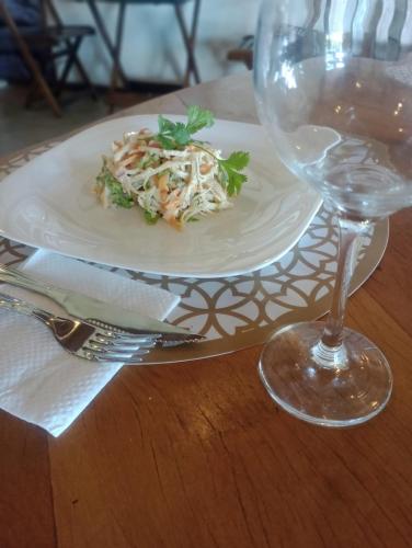 a plate of food and a wine glass on a table at RESONAMUH - Hostel in São Pedro da Aldeia