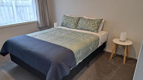 a bedroom with a bed with a blue comforter and a table at South City Accommodation unit 4 in Invercargill