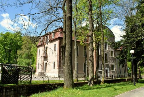 an old house with a fence and trees at Muza in Duszniki Zdrój