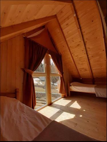an attic room with a large window in a cabin at Villa in Rugove, Kosovo in Lekaj
