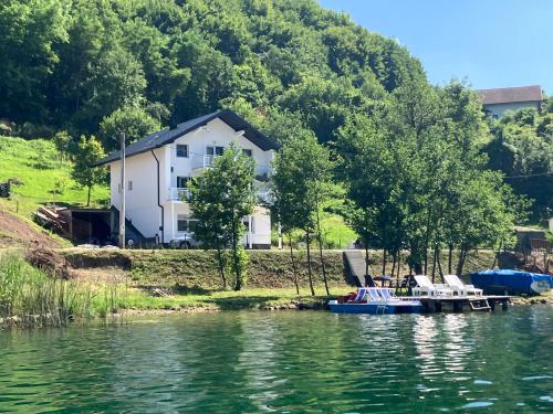 een huis aan de oever van een meer met een boot bij Villa Pliva Lake Jajce in Jajce