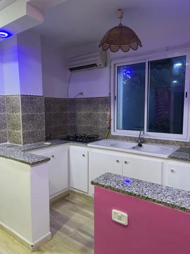 a kitchen with white cabinets and a window at cosy Furnished appartment in Ez Zahra