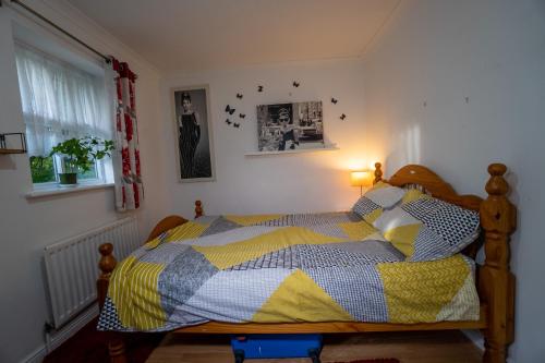 a bedroom with a bed with a yellow and blue quilt at Super room with free parking 400 Mbps Internet in London