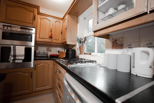 a kitchen with wooden cabinets and a stove top oven at Super room with free parking 400 Mbps Internet in London