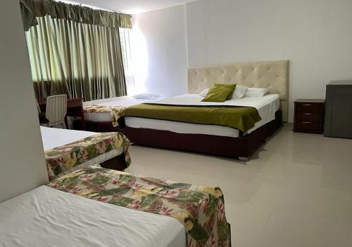 a hotel room with two beds and a window at Hotel Caribe Rodadero in Santa Marta