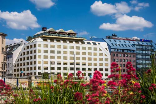 a white building with pink flowers in front of it at Radisson RED Hotel, Vienna in Vienna