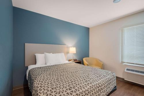 a bedroom with a bed and a blue wall at WoodSpring Suites Bellflower - Los Angeles in Bellflower