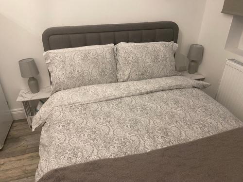 a bed with a white comforter and two pillows at Exeter Garden for 2 in Ilford