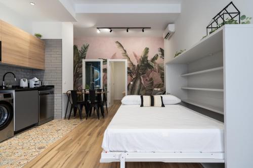 a bedroom with a white bed and a kitchen at Beach Apartments Valencia in Valencia