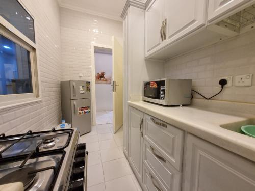 a kitchen with a stove and a microwave at شقة فخمة غرفتين وصالة متكاملة قرب لافاندا بارك in Abha