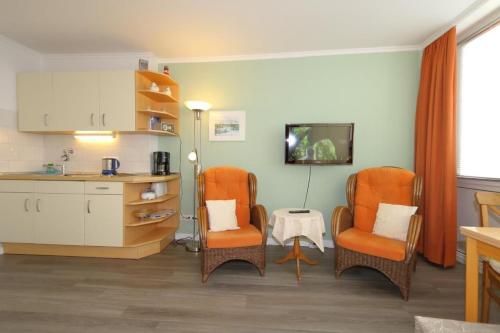ein Wohnzimmer mit 2 Stühlen und eine Küche in der Unterkunft App. Rüter 57 in Westerland