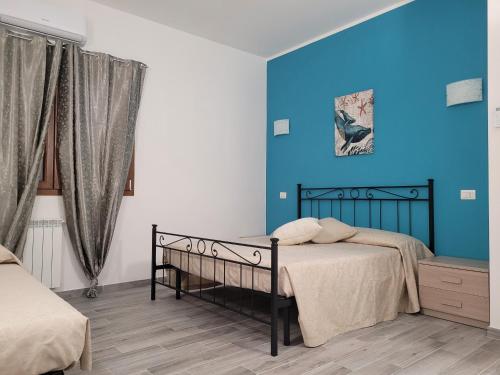 1 dormitorio con 1 cama con pared azul en Rooms da Pisicchio, en Fiumicino