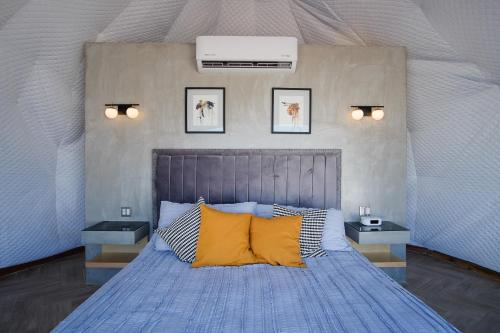 una camera da letto con letto blu e cuscini gialli di Cúpulas Del Valle by Villa De La Rosa a Ensenada