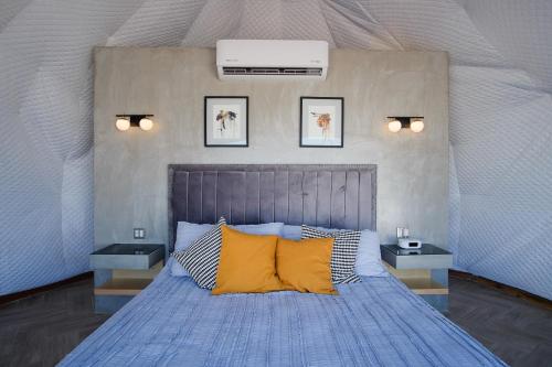 Un dormitorio con una cama azul con almohadas amarillas en Cúpulas Del Valle by Villa De La Rosa en Ensenada
