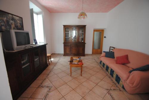 a living room with a couch and a tv at Country House Villa Geminiani in Montalto delle Marche