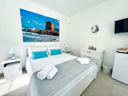 a white bedroom with a large bed and a flat screen tv at Torre Pozzillo Beach in Cinisi
