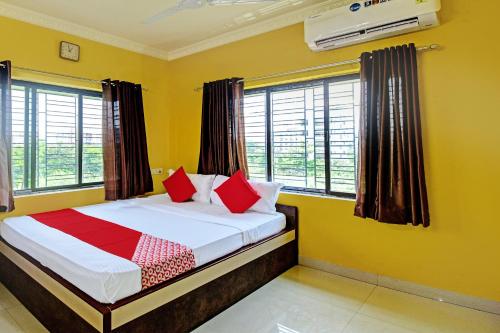 a bedroom with a bed with red pillows and windows at Flagship JMD Upasana 2 in Kolkata