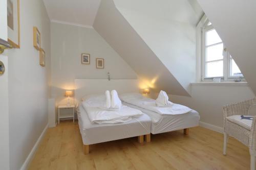 een witte kamer met 2 bedden op een zolder bij Landhaus-Friedrichshain-Theodor-Storm in Westerland