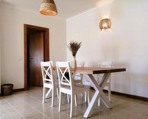 a dining room with a wooden table and white chairs at Nalu House Baleal - by the beach in Baleal