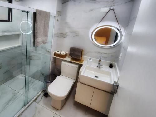 Un baño con inodoro, lavabo y espejo. en Sonho de apartamento pé na areia, en Porto de Galinhas