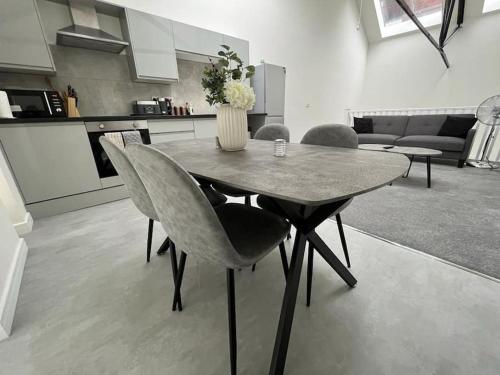 a dining room table with a vase of flowers on it at Modern Loft Apartment in Rotherham