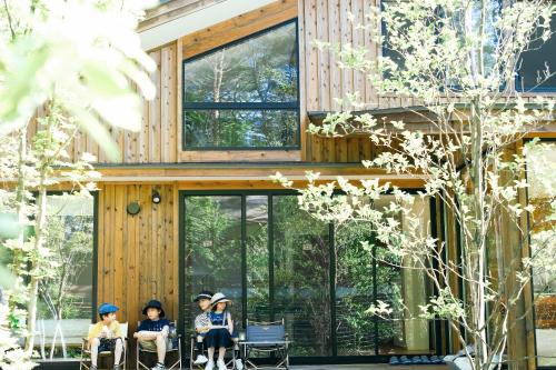 un grupo de personas sentadas en sillas frente a una casa en Karuizawa Forest Seasons Villa en Karuizawa