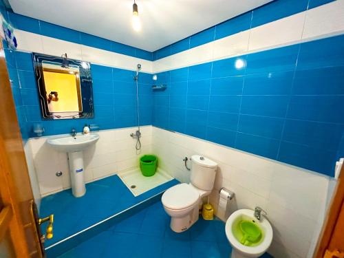 La salle de bains bleue et blanche est pourvue de toilettes et d'un lavabo. dans l'établissement Résidence Jawhara, luxe, piscine et en face à la mer, à Oued Laou
