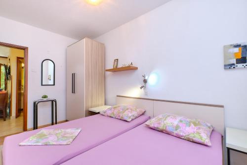 a bedroom with a purple bed with two pillows at Apartment Artatore 2509a in Čunski