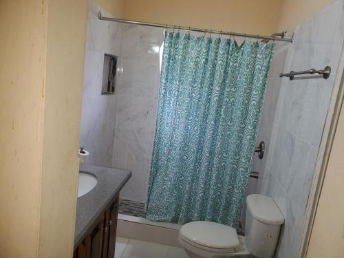 a bathroom with a blue shower curtain and a toilet at Alian's Comfort Stay in Montego Bay