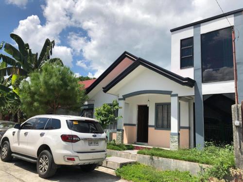 een witte auto geparkeerd voor een wit huis bij Air-conditioned Home in Davao City