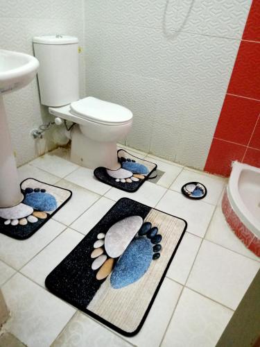 a bathroom with a toilet and three mats on the floor at شاليه ديمورا عائلات فقط Dimora Chalet Only Family in Dawwār Muḩammad Abū Shunaynah