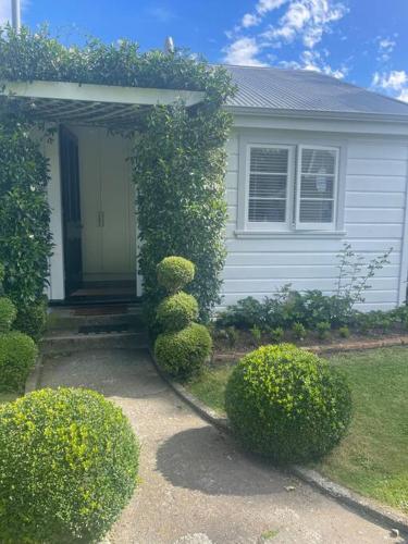 a white house with bushes in front of it at Alloa Petite in Fernside