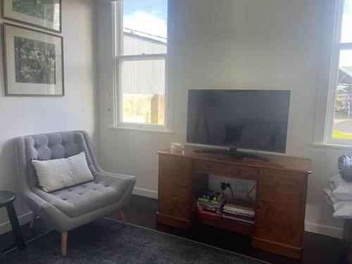 a living room with a chair and a flat screen tv at Alloa Petite in Fernside