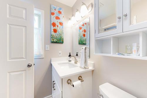 a white bathroom with a sink and a toilet at Compass Rose in Topsail Beach