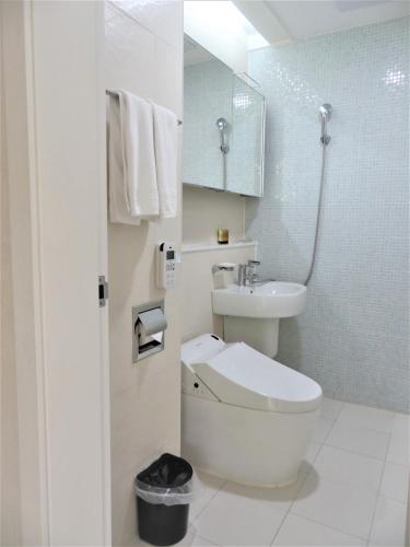 a white bathroom with a toilet and a sink at Healthcare Town Resort in Seogwipo