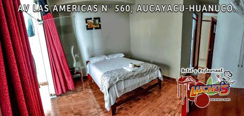 een slaapkamer met een bed en een tafel met rode gordijnen bij HOTEL LUCHO'S in Aucayacu