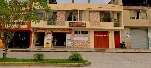 un edificio con puertas rojas en una calle de la ciudad en HOTEL LUCHO'S, en Aucayacu