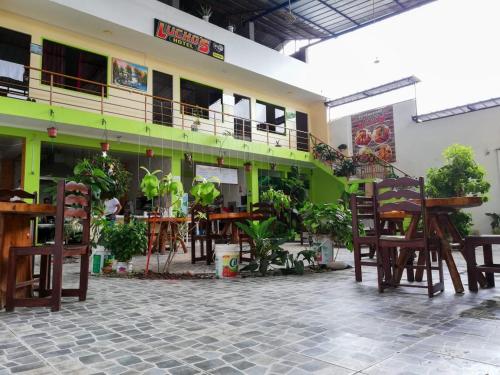 un patio avec des tables et des chaises dans un bâtiment dans l'établissement HOTEL LUCHO'S, à Aucayacu