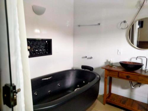 uma banheira preta na casa de banho com um lavatório em Pousada Nascente do São Francisco em Vargem Bonita