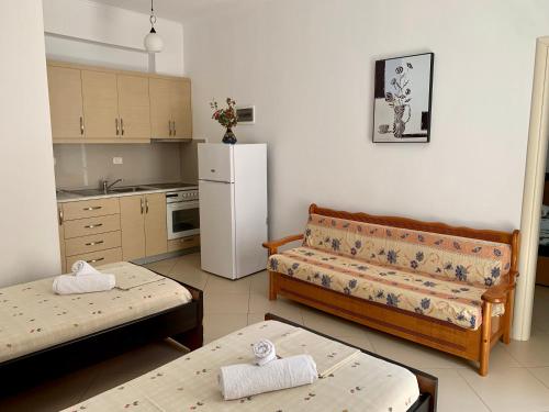 een woonkamer met 2 bedden en een witte koelkast bij Duka Apts in Sarandë