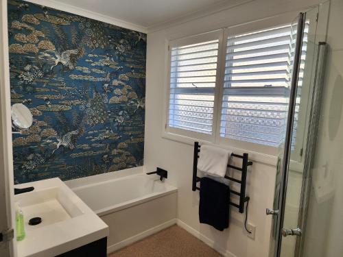 baño con bañera, lavabo y ventana en 253 on HIGHGATE, en Dunedin