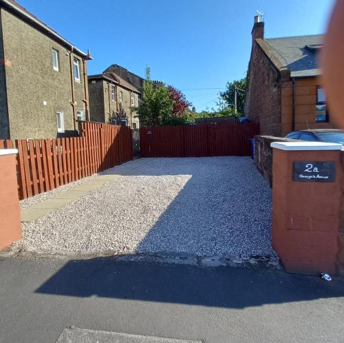 a driveway with a fence and a trash can at J & S Apartments in Ayr