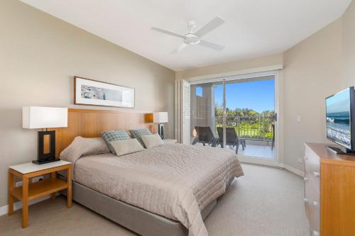 a bedroom with a bed and a television and a balcony at Resort On The Beach 5118 with resort Pool in Kingscliff