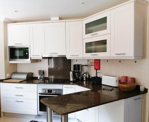 a kitchen with white cabinets and a black counter top at Praia d'el Rey The Golf & Beach Villa in Óbidos