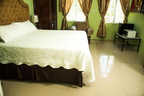 a bedroom with a large bed with a white blanket at Dela de-Rose Guest House Negril Jamaica in Negril