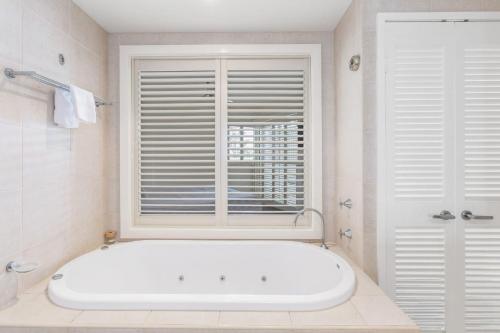 een badkamer met een wit bad en een raam bij RESORT ON THE BEACH 1219/20 in Kingscliff