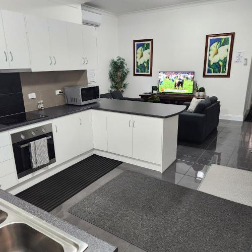 a kitchen with white cabinets and a living room at City Villa 39 Blende st Broken Hill NSW 2880 in Broken Hill